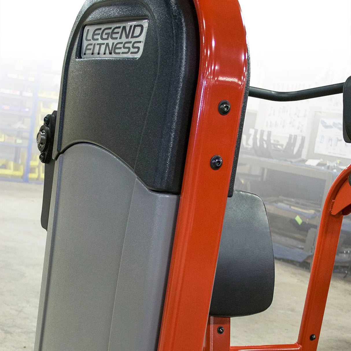 Close-up of a red and gray Legend Fitness exercise machine with a blurred background