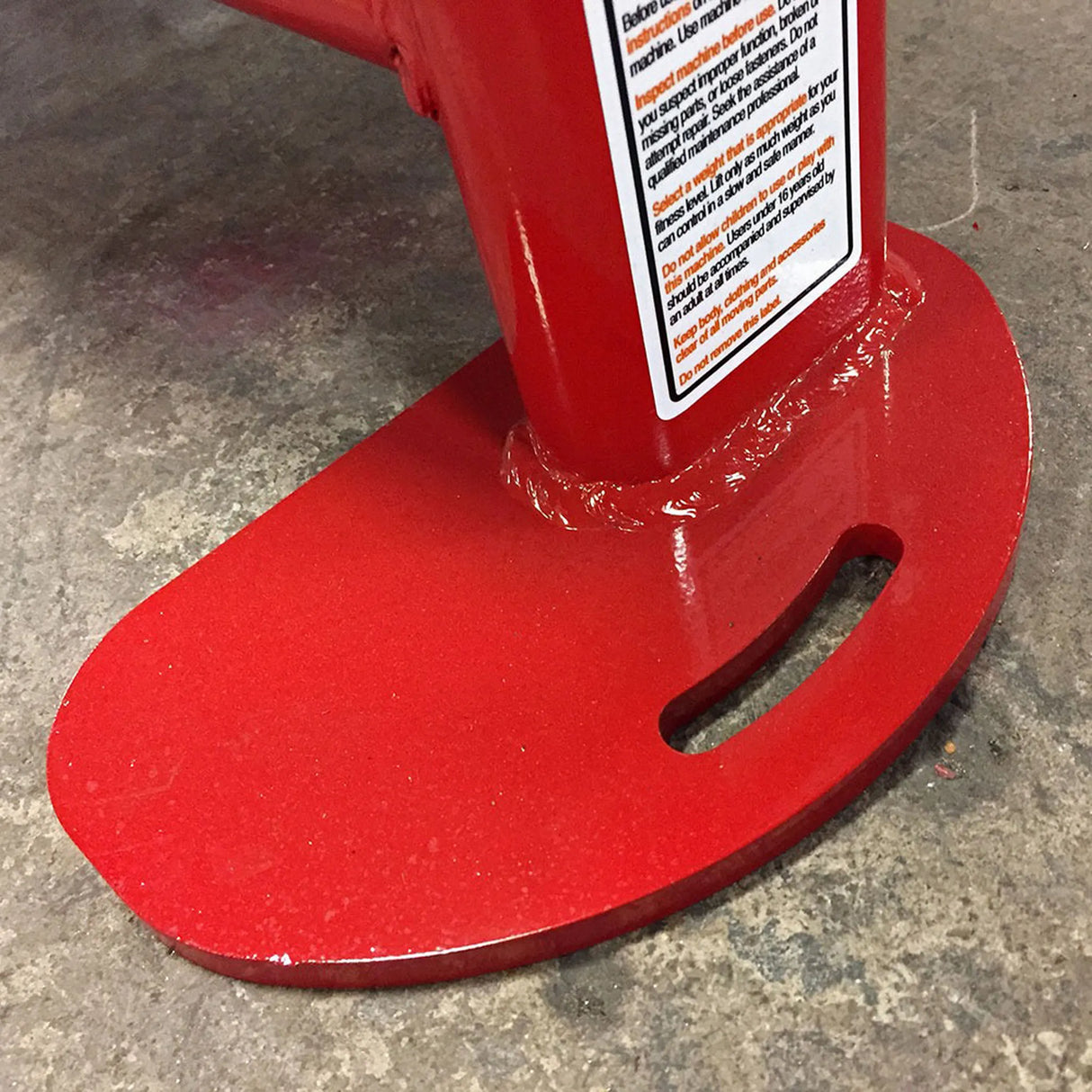 Red metal stand with a warning label on a concrete floor