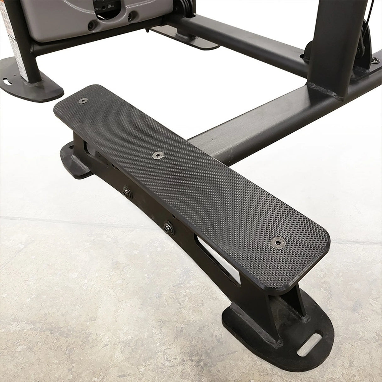 Black footrest for a gym machine on a white background