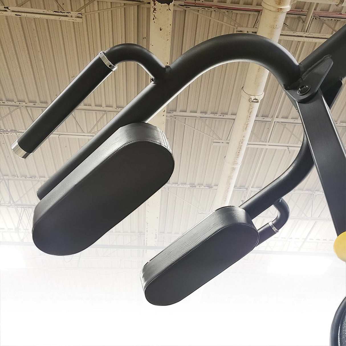 Black exercise handles on a gym machine with a ceiling in the background