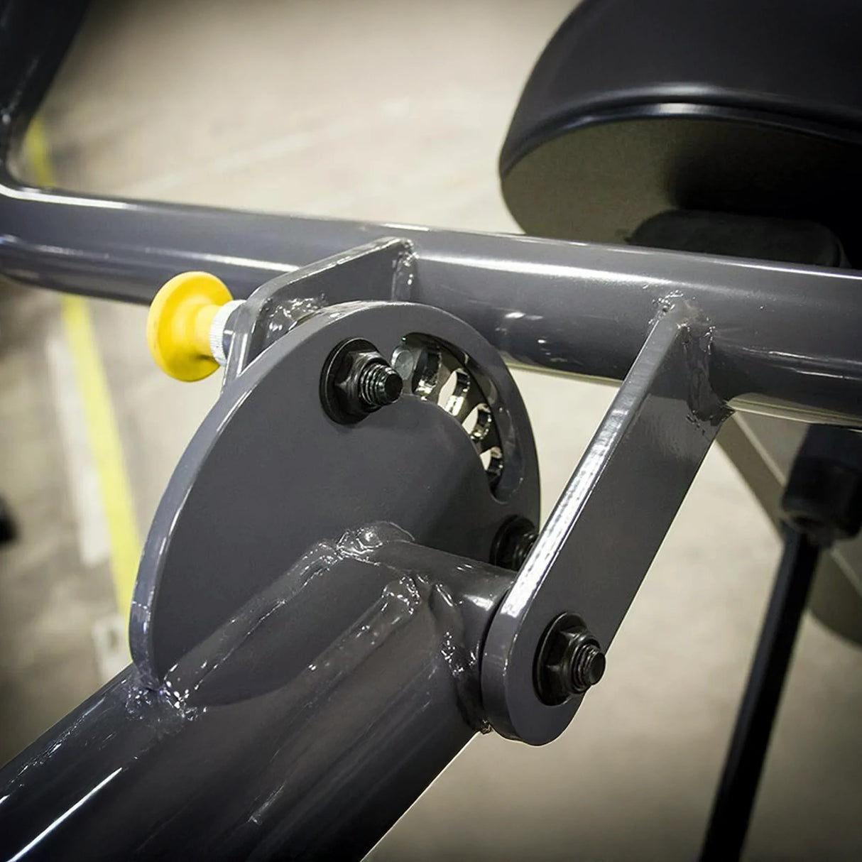 Closeup of some metal components with a yellow pop-pin on a piece of gym equipment
