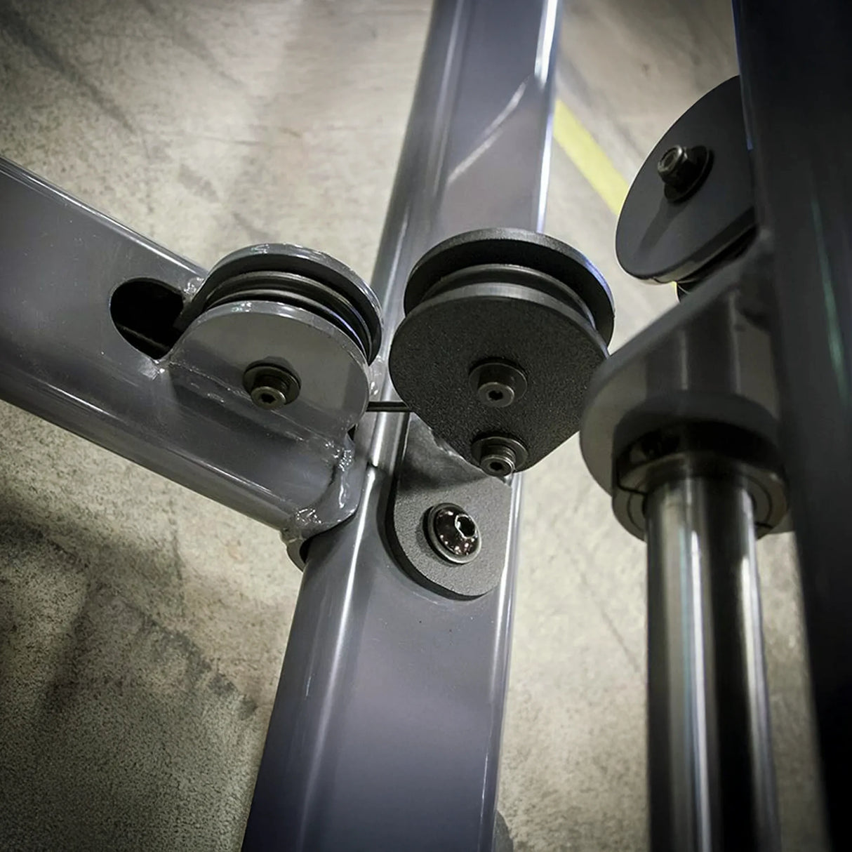 Close-up of a gray metal frame pulleys on a concrete floor.