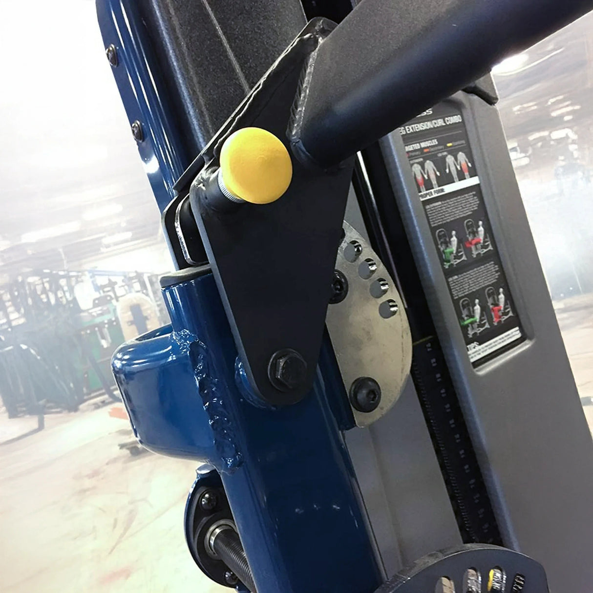 Close-up of a blue exercise machine with a yellow pop-pin and a black instructional placard