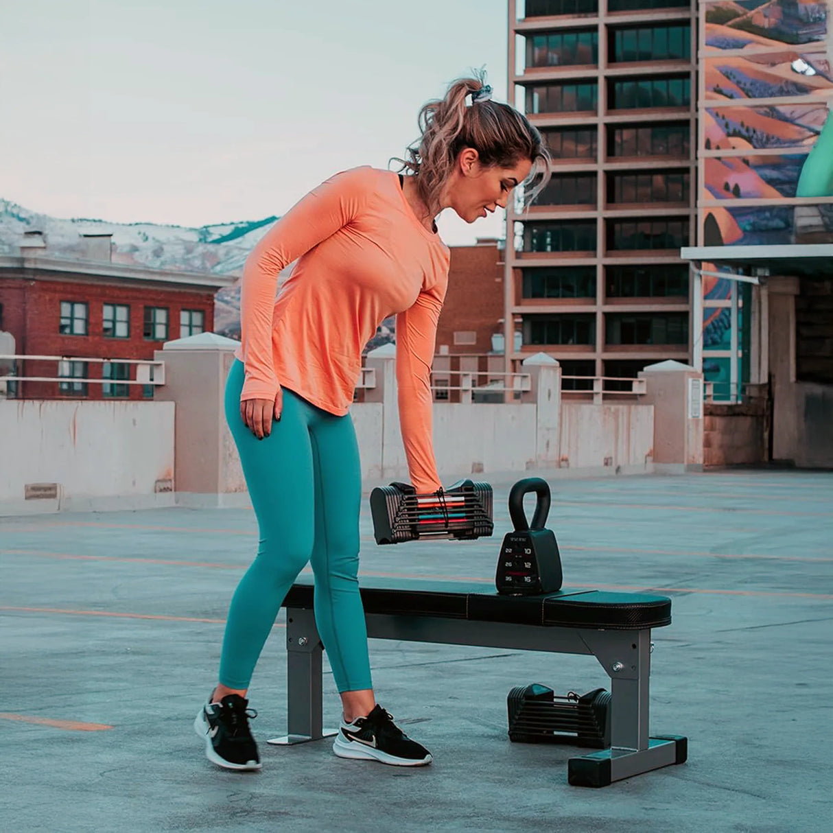 A woman placing a dumbbell on a PowerBlock Fold Up Portable Travel Bench