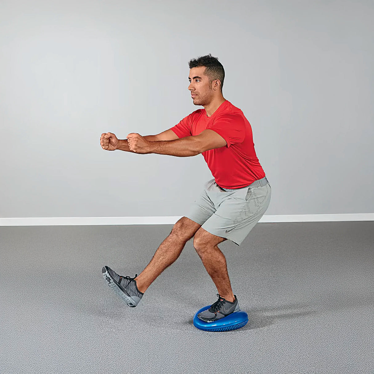 Man balancing on one leg on inflatable balance disc pillow pad by Perform Better