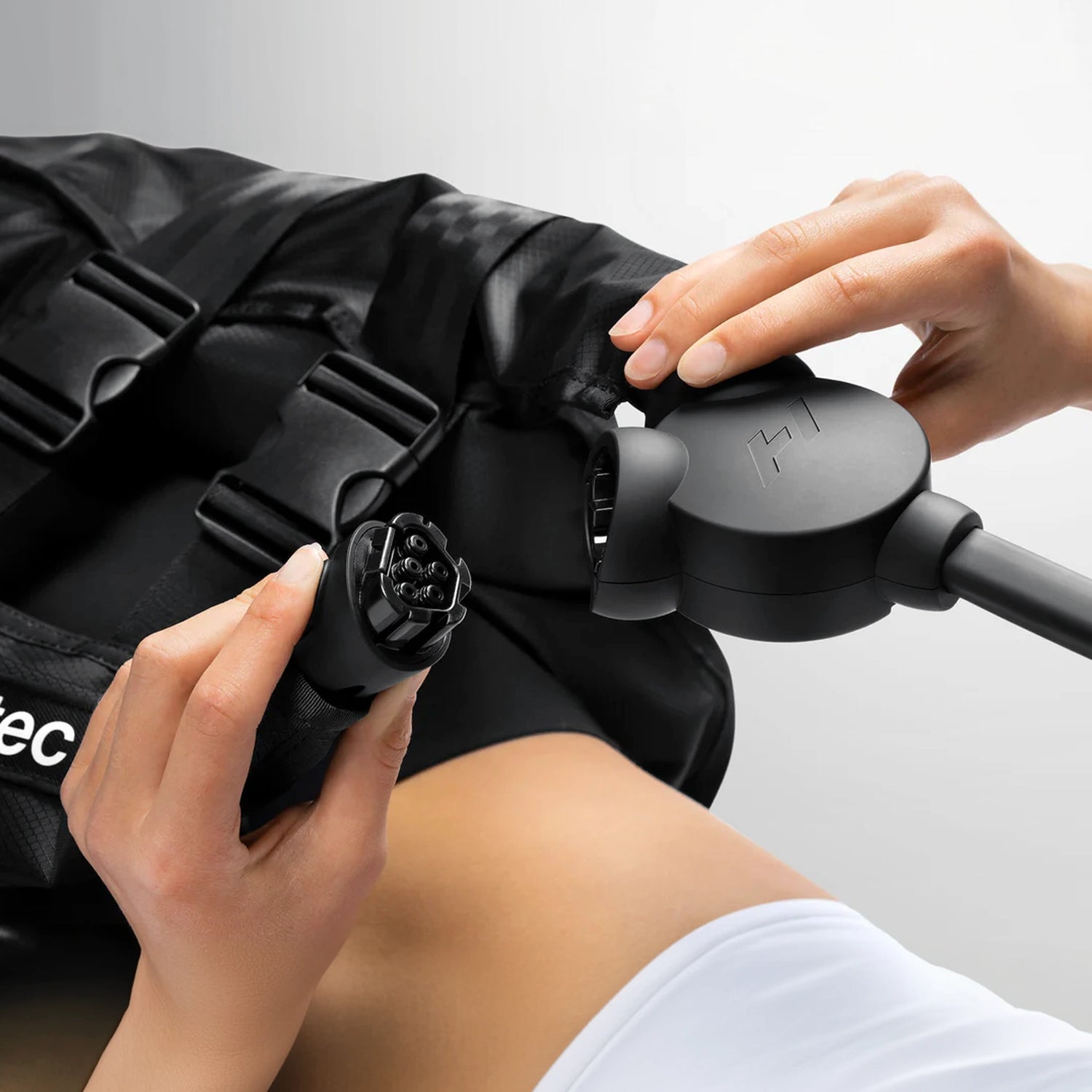 A closeup image of someone plugging in an air hose on a pair of Normatec Hip Attachments for compression and massage.