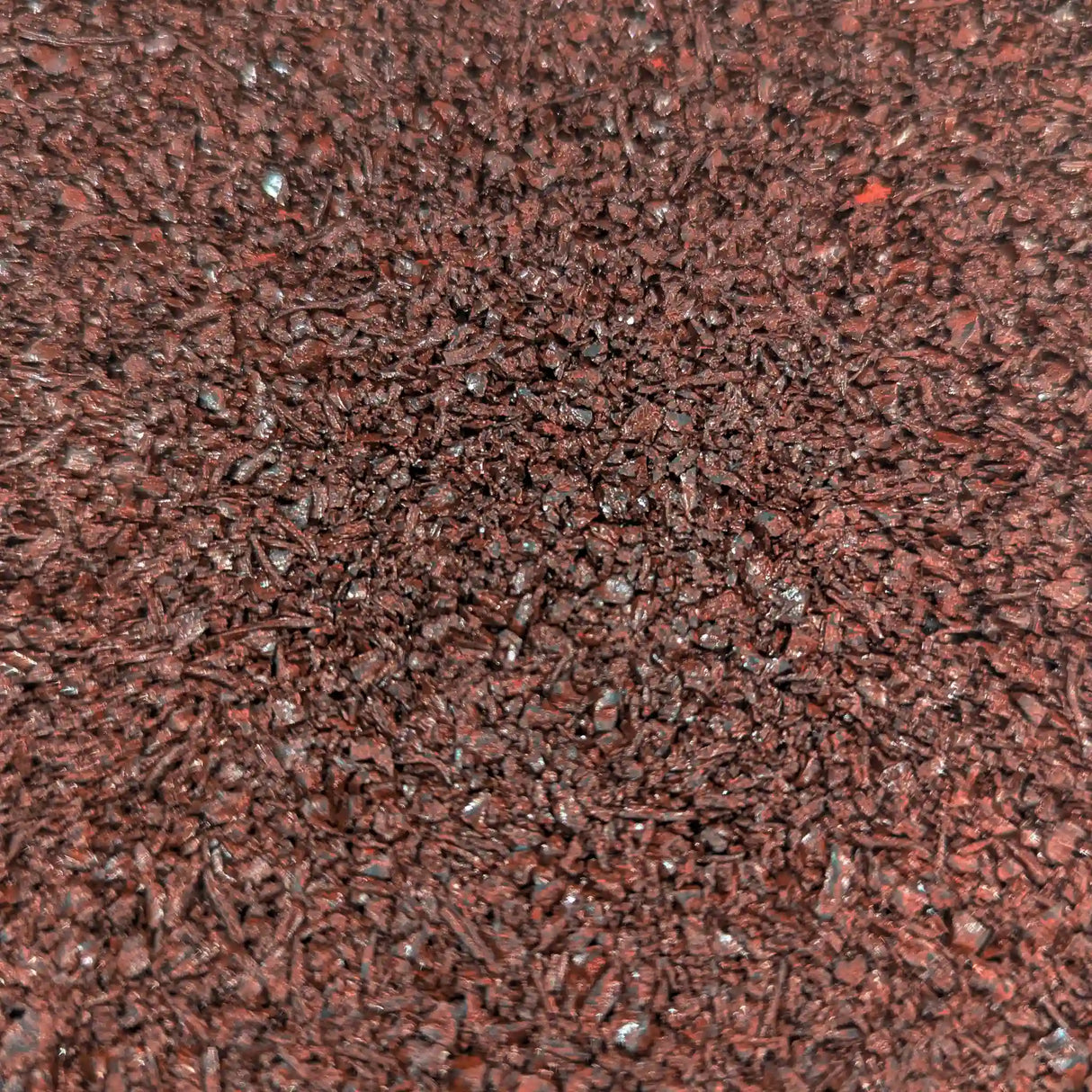 Close-up view of the ECORE Rubber Paver, 1" (24 mm) by ECORE Athletic, showing its textured surface covered with small, dark reddish-brown granules or flakes for a rough, uneven appearance.