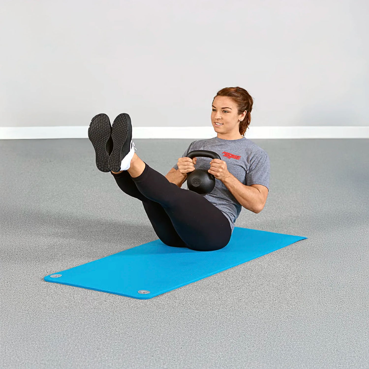 Woman doing kettlebell workout on blue foam exercise mat by Perform Better