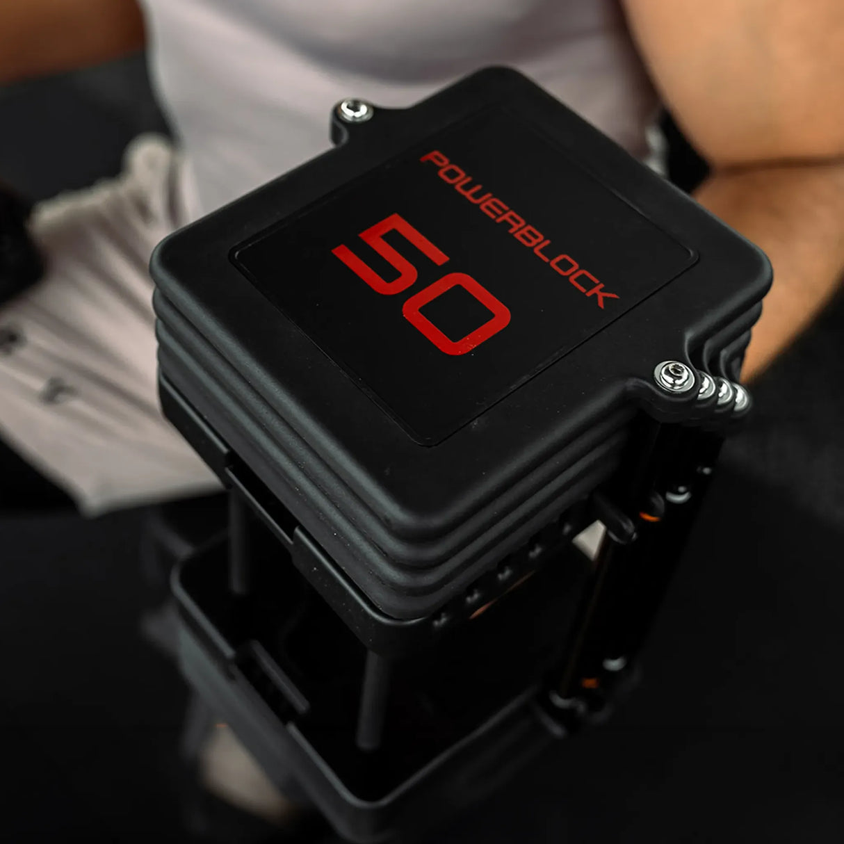 A man holding a pair of PowerBlock Commercial Pro 100 Dumbbells