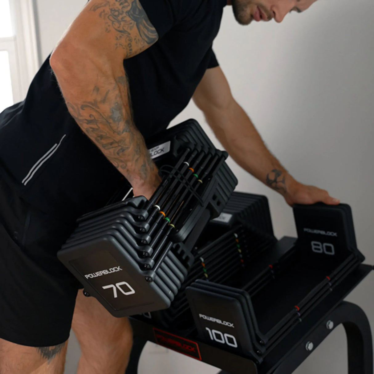 A man picking up a PowerBlock Pro 100 dumbbell
