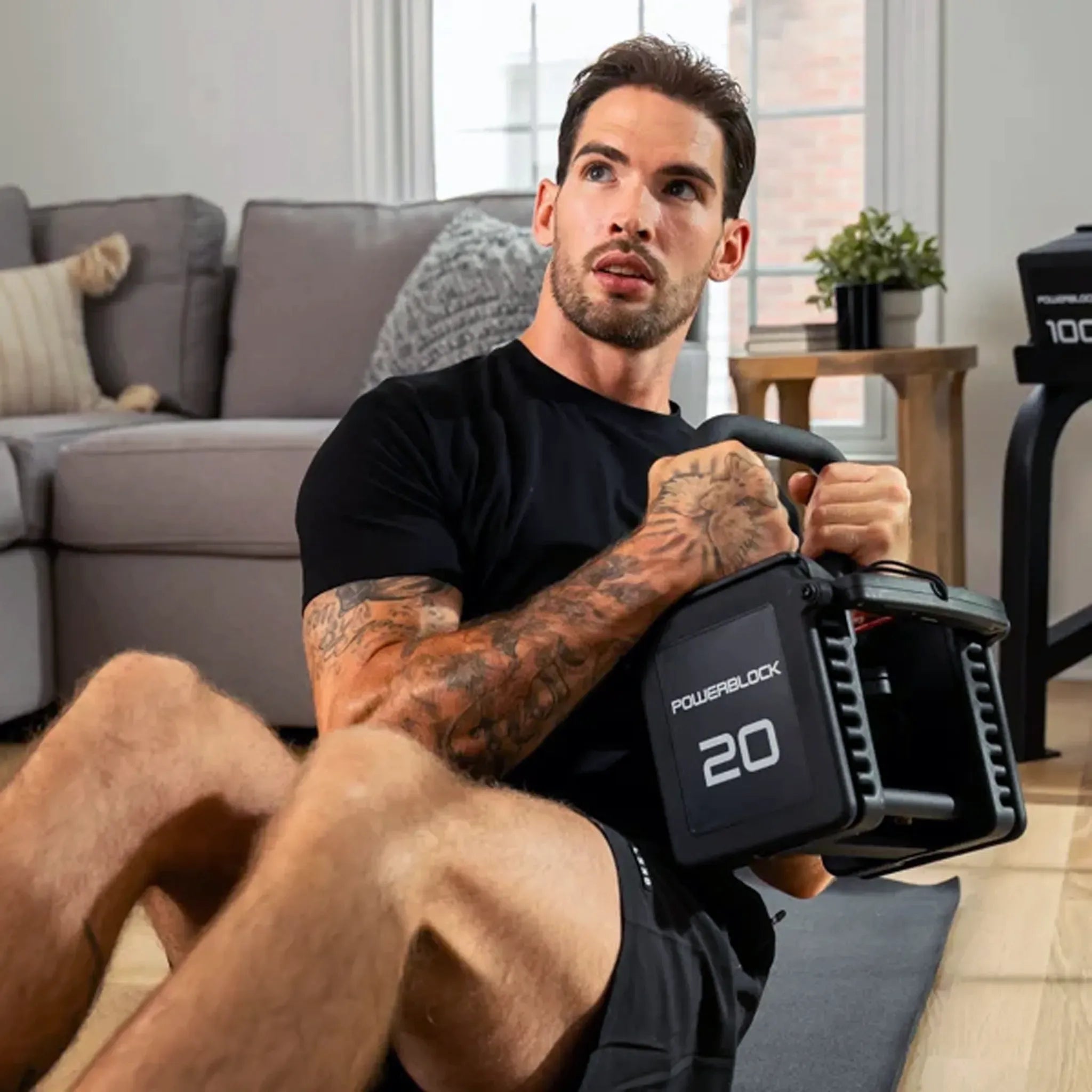 A man doing a core workout with a PowerBlock Pro 100 Kettlebell Handle in a PowerBlock dumbbell