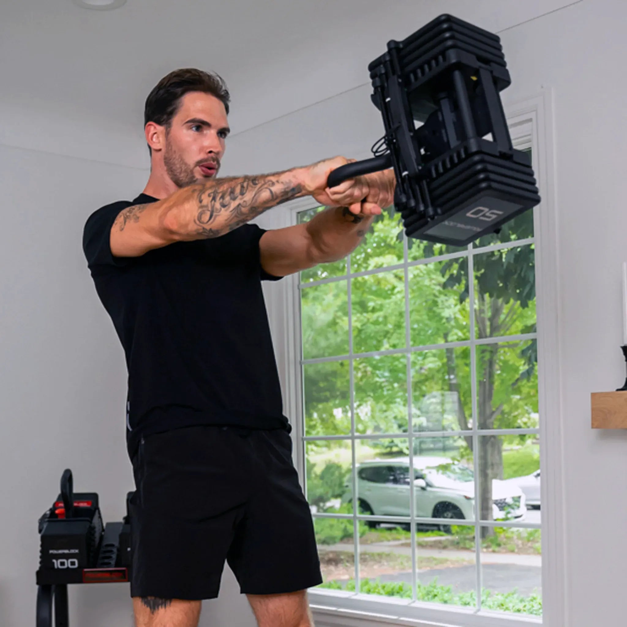 A man swinging a PowerBlock Pro 100 Kettlebell Handle in a PowerBlock dumbbell