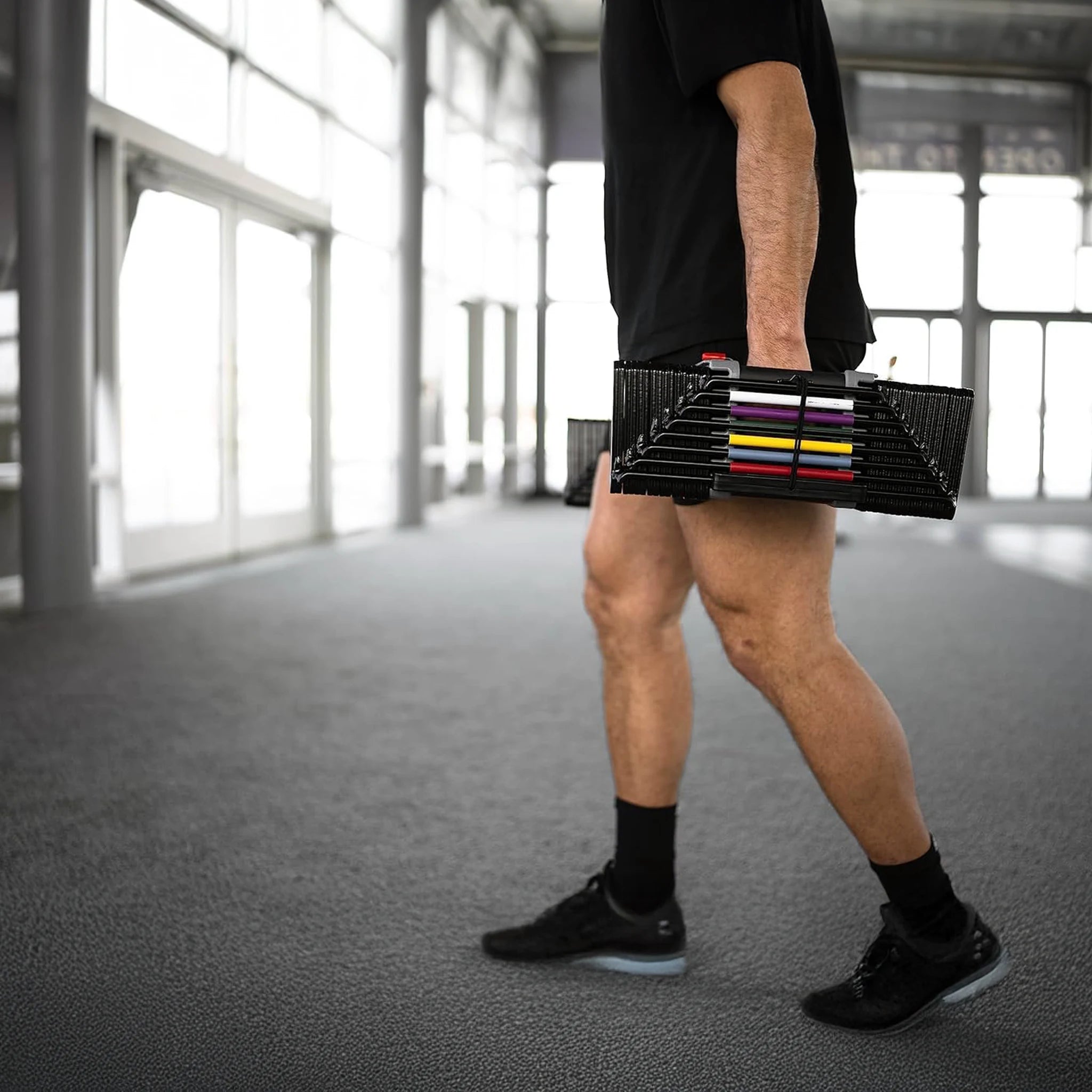 A man carrying a pair of PowerBlock Elite USA 90 dumbbells
