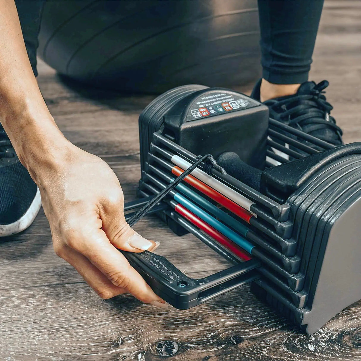 A woman adjusting the pin on a PowerBlock Sport 24 Dumbbell