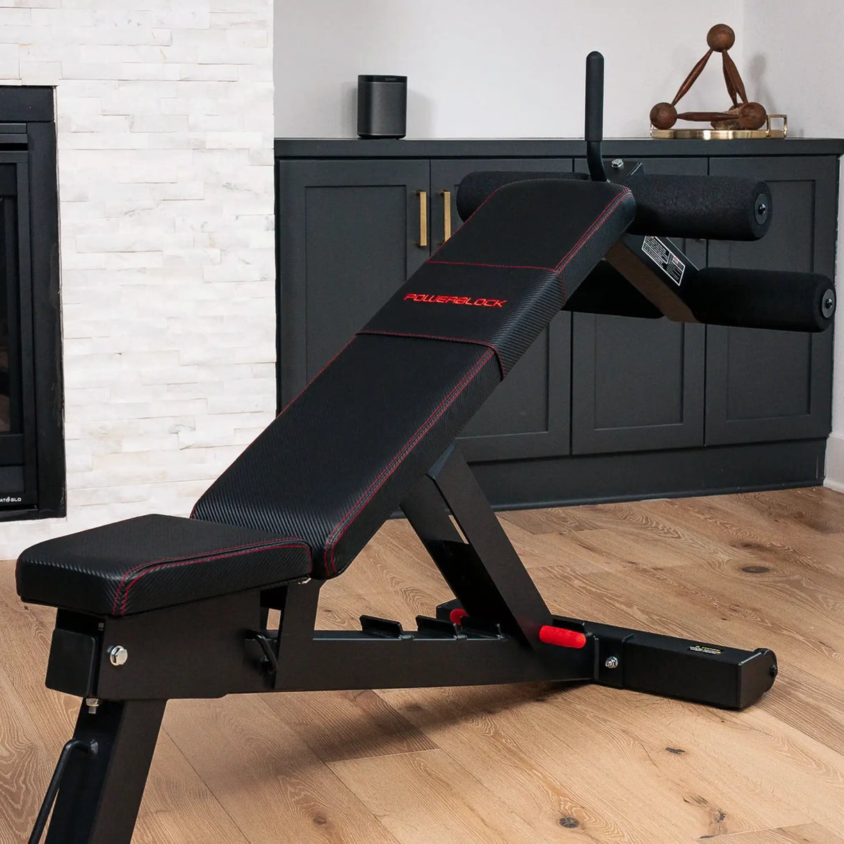 A PowerBlock bench with a sit-up ab and core attachment attached to the back