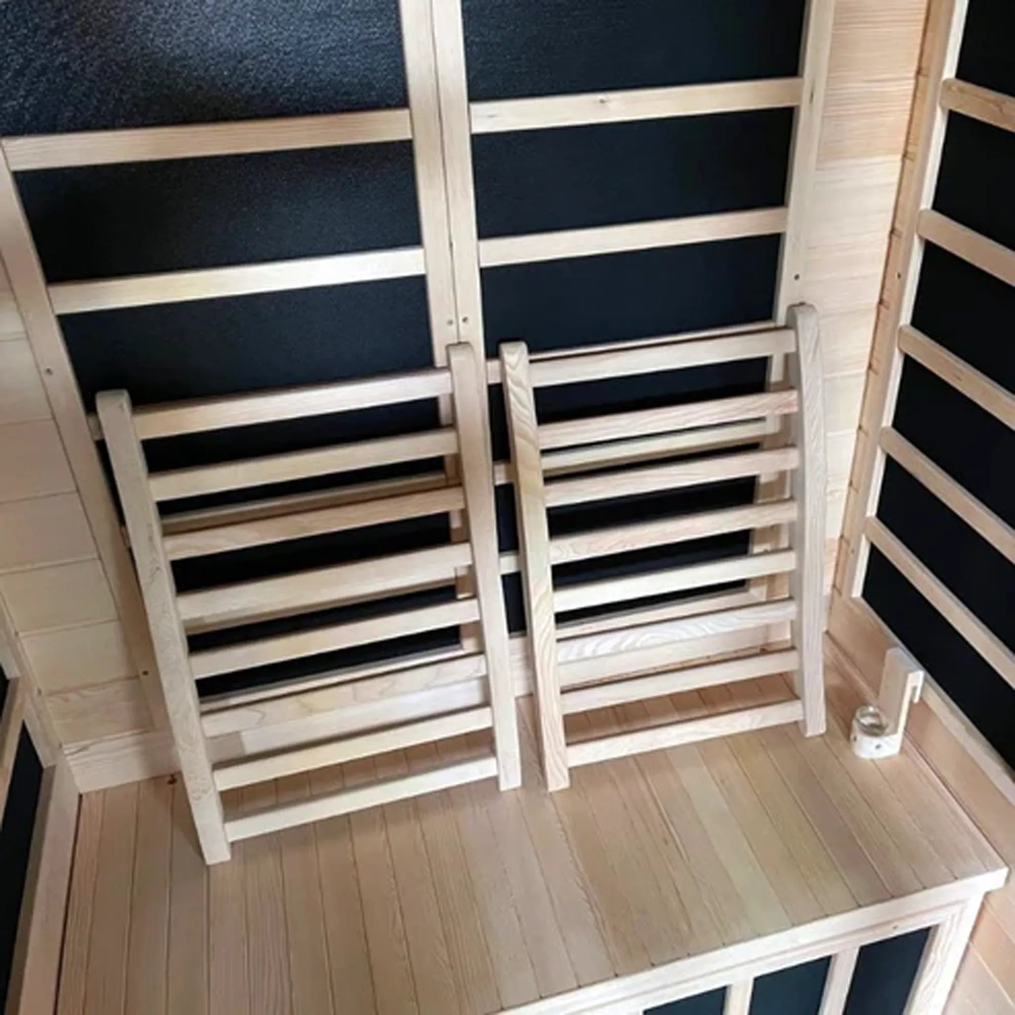 Two wooden backrests with parallel wooden rungs inside of a sauna