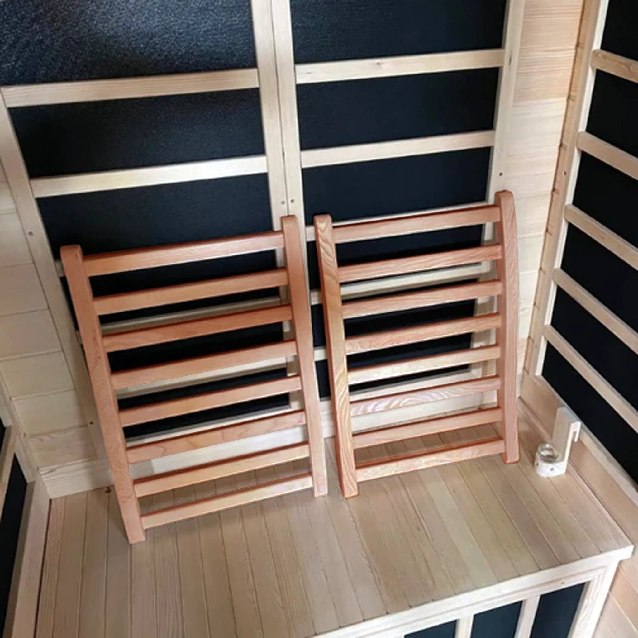 Two wooden backrests with parallel wooden rungs inside of a sauna