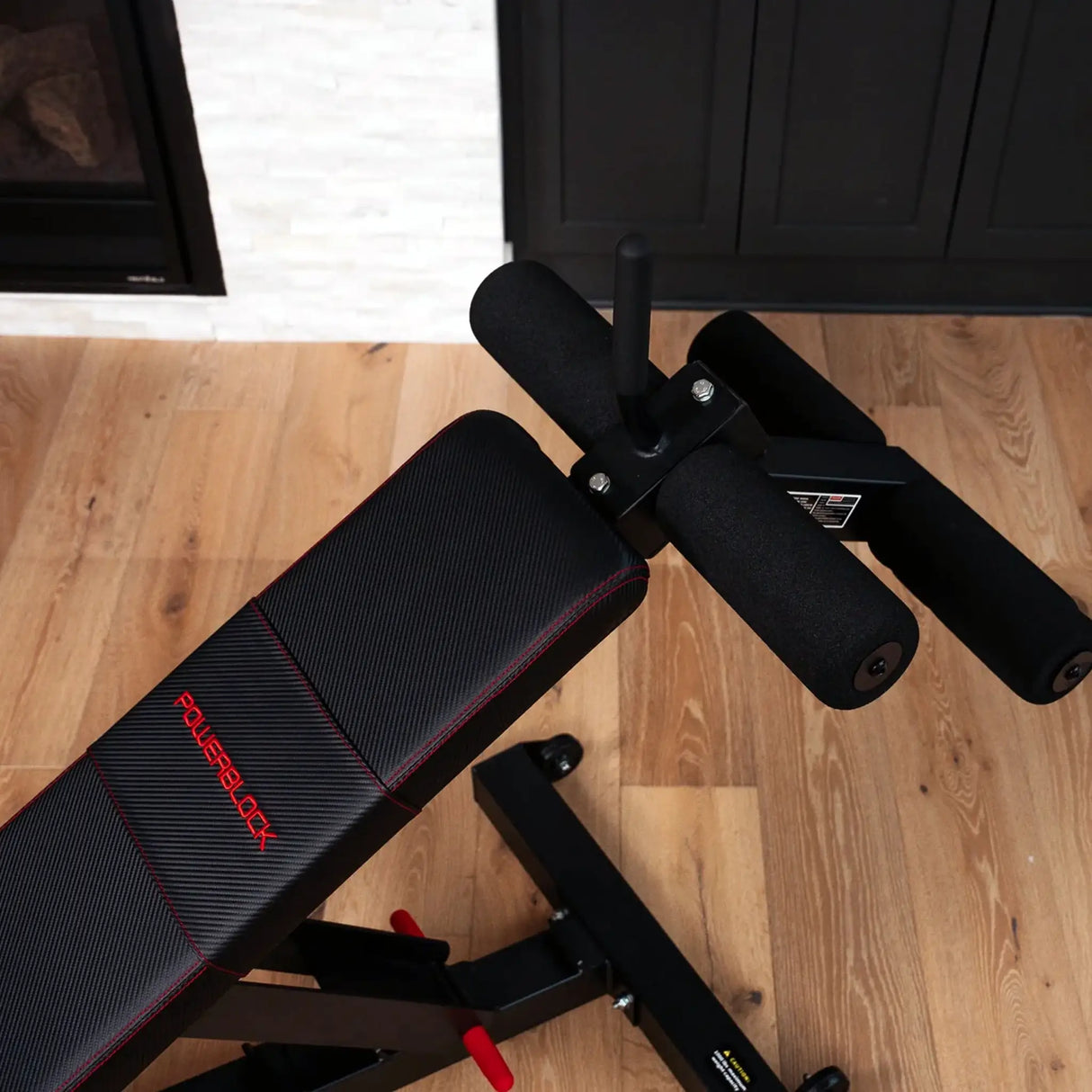 A PowerBlock bench with a sit-up ab and core attachment attached to the back