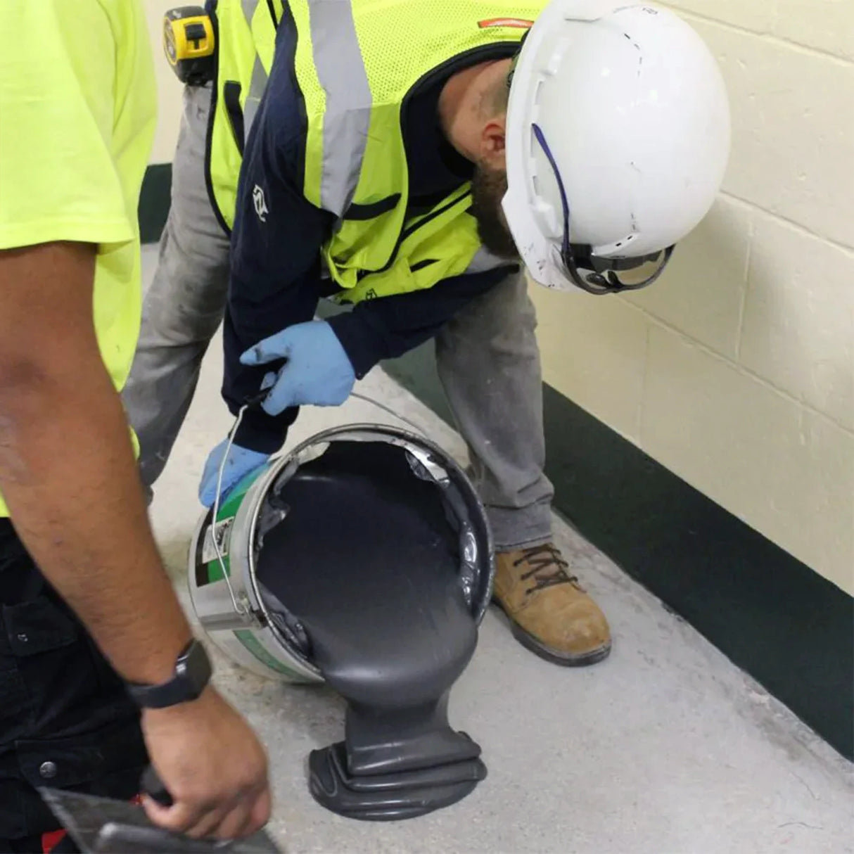 Person in safety gear pouring Ecore E-Grip III to the foundation of a room