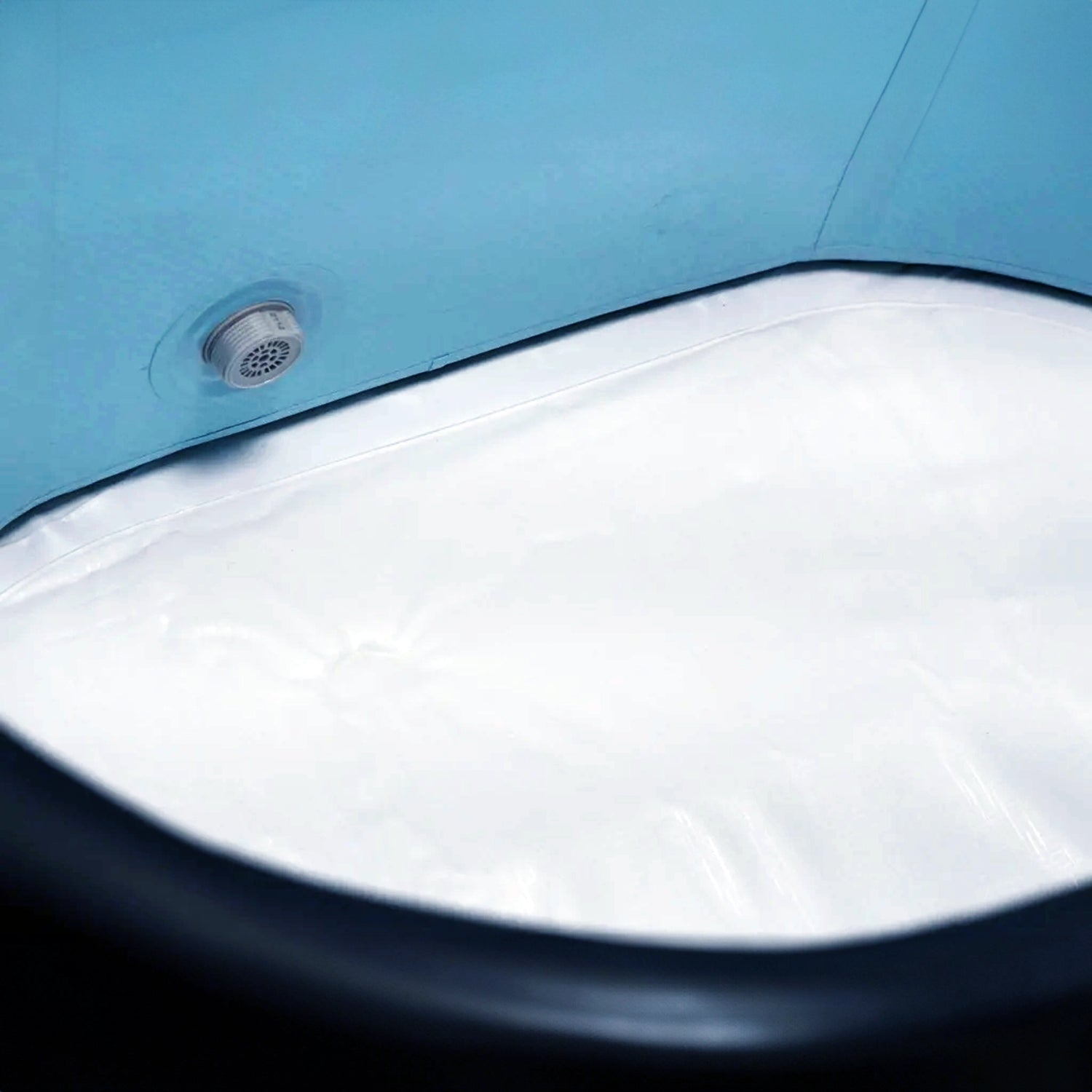 Closeup image of the inside of an inflatable cold plunge with a dark blue exterior, light blue inside walls, and white floor