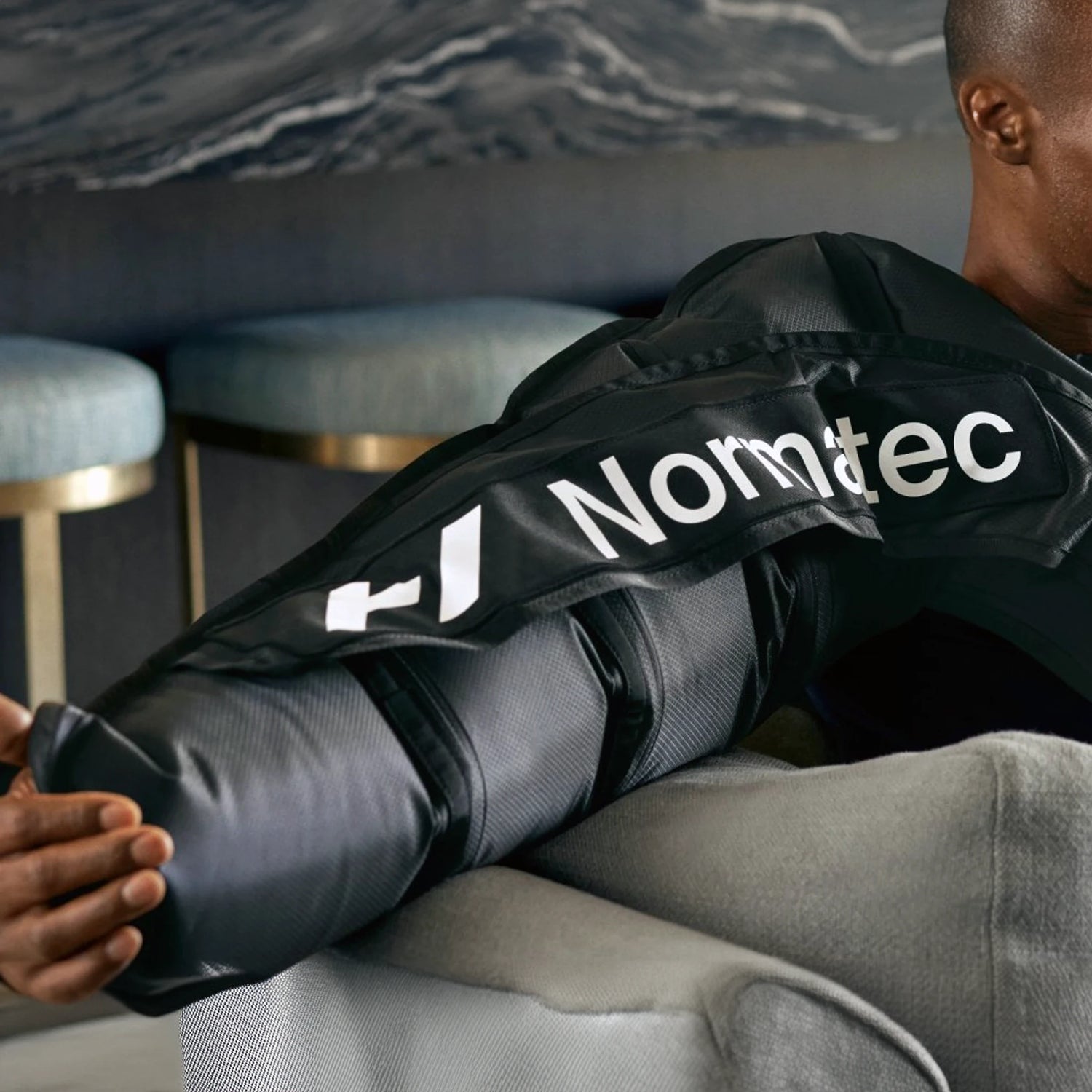 A man wearing a Normatec arm compression sleeve on his right arm.