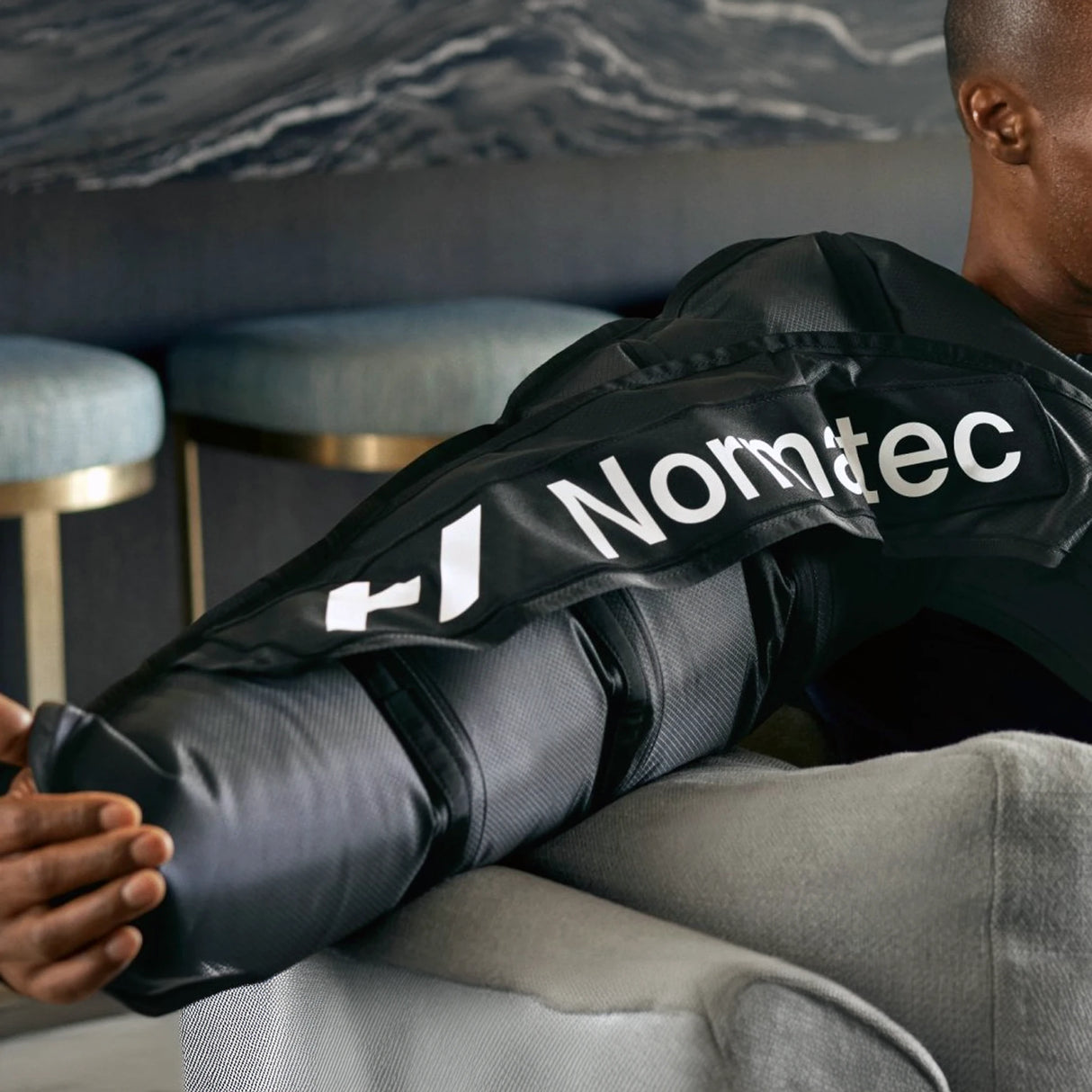 A man wearing a Normatec arm compression sleeve on his right arm.