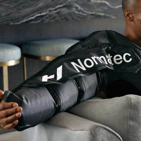 A man wearing a Normatec arm compression sleeve on his right arm.