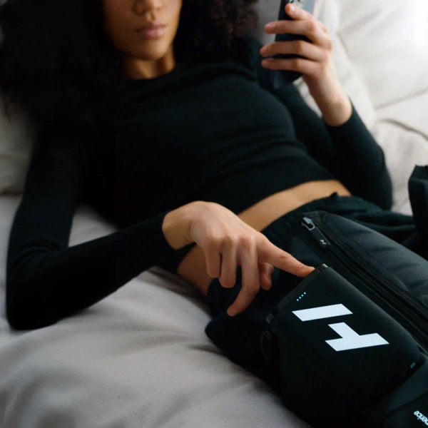 A woman adjusting her Normatec Elite Legs while lying down