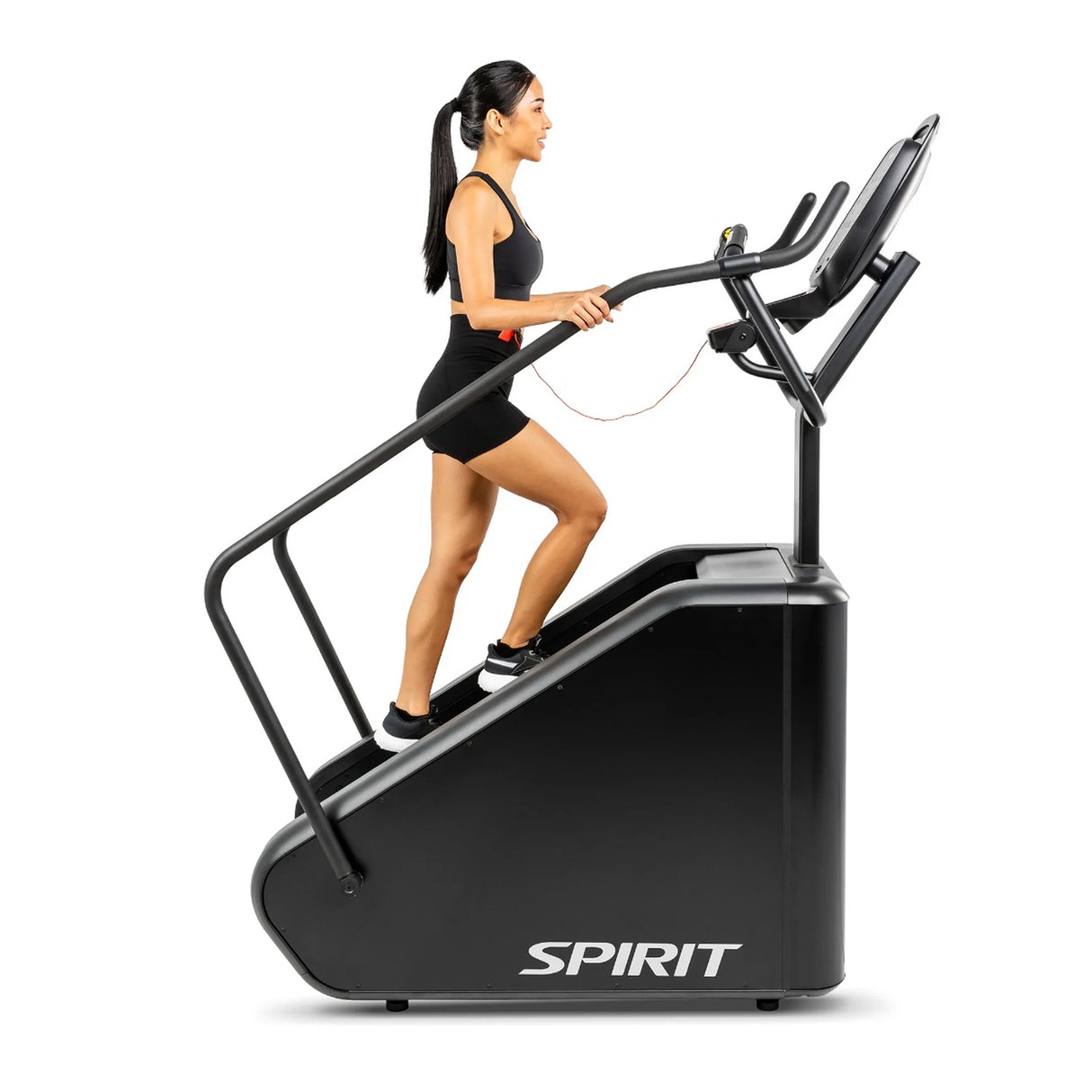 A woman climbing the Spirit Fitness CSC880 Stair Climber, gripping the side handrail mid-stride.
