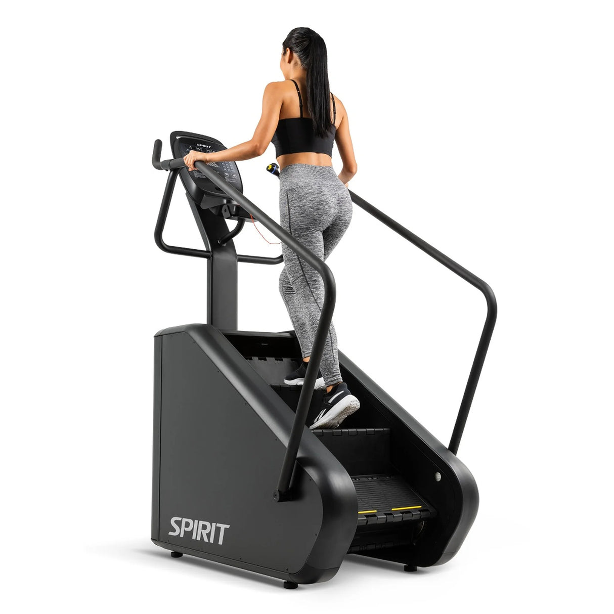Rear-angle view of a woman climbing the Spirit Fitness CSC880 Stair Climber wearing grey leggings.