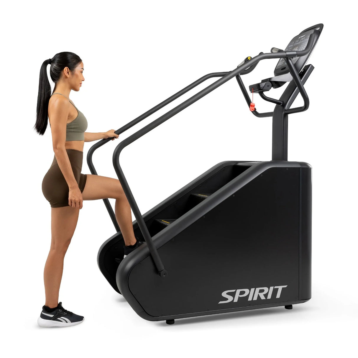 Side view of a woman stepping onto the Spirit Fitness CSC880 Stair Climber, holding the handrail.