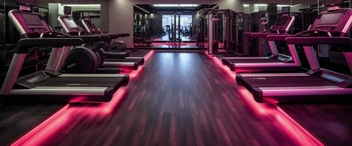 high end modern gym with cardio on the left and right and a lit up floor with pink neon lights in the middle