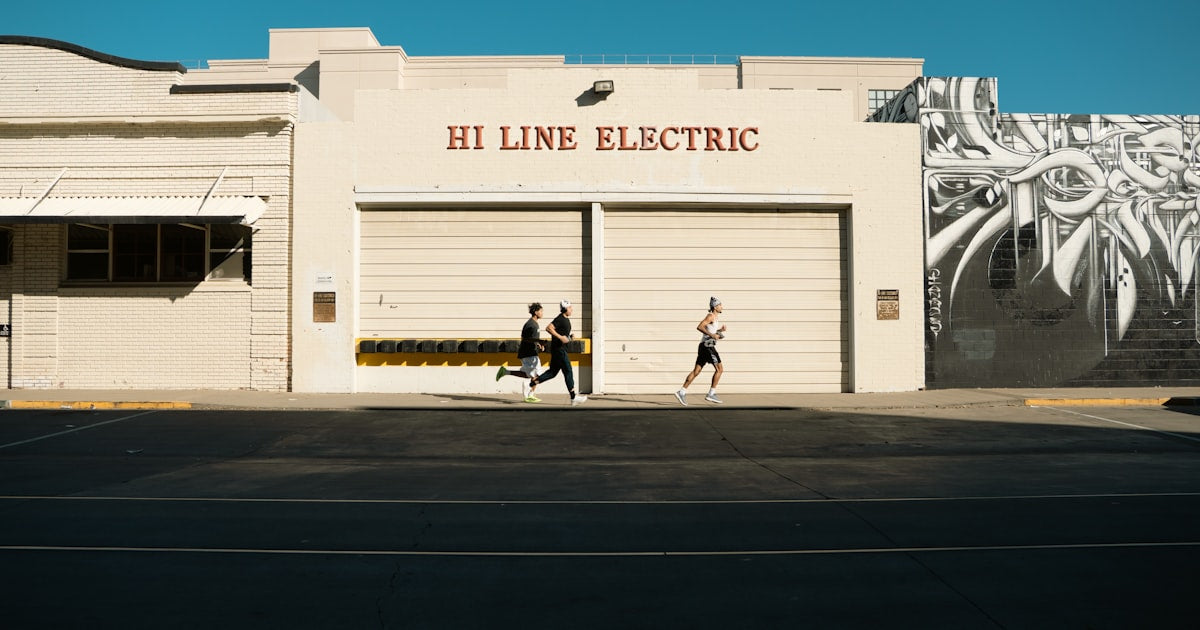 Three people running in front of a building.