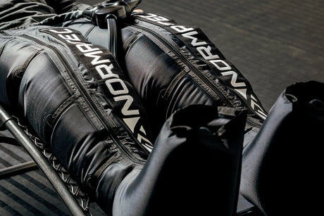 A closeup image of someone wearing Normatec compression leggings while sitting in a reclined chair.