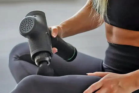 A woman using a Hypervolt massage gun above her knee.
