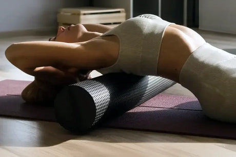 A woman rolling out her upper back and shoulders on a foam roller.