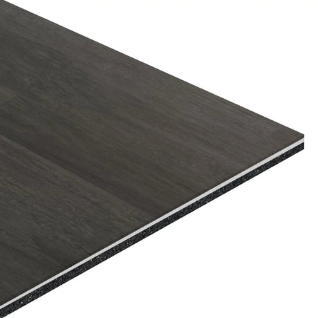 A close-up of the ECORE Athletic Balanced Motivate Laminate Roll - 7mm Class 1 Flooring highlights its rectangular, dark surface with a wood-like finish and visible underlying core layers.