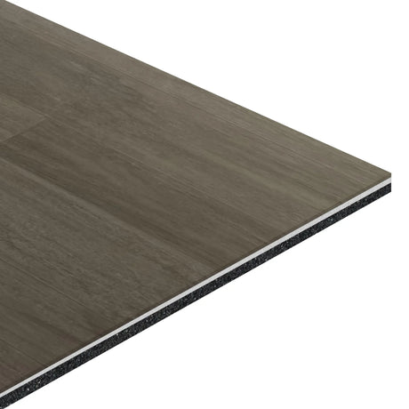 A close-up of the ECORE Balanced Motivate Laminate Roll - 7mm Class 1 Flooring by ECORE Athletic, featuring a rectangular piece with wood-like grey and brown tones, layered construction, and a cross-section revealing its multiple layers.