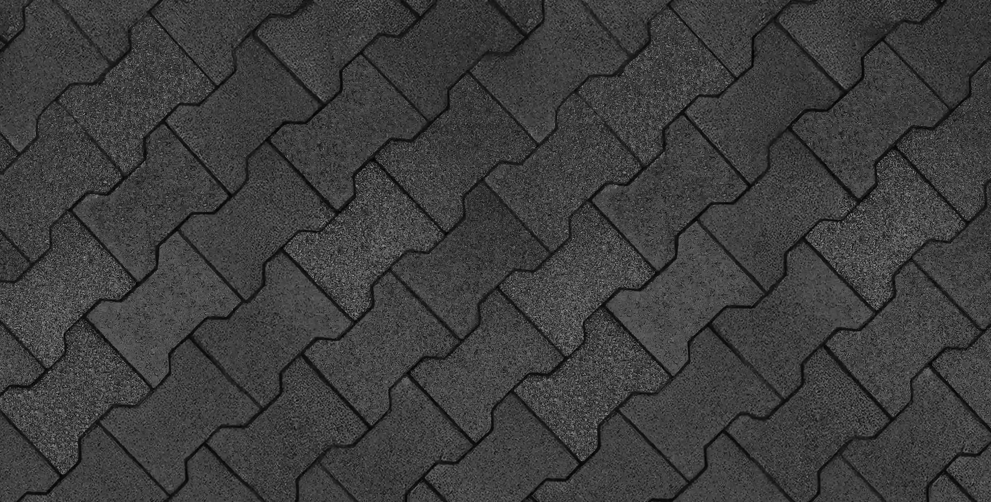 An overhead top-down view of a floor made from black rubber pavers in an interlocking pattern