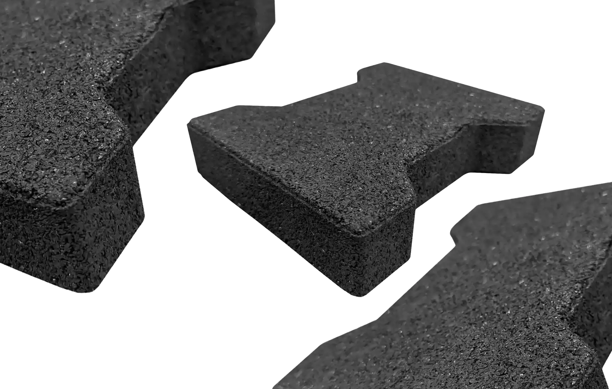 Three black rubber pavers with one centered and further away and two on the edges not fully in the frame and closer to the camera