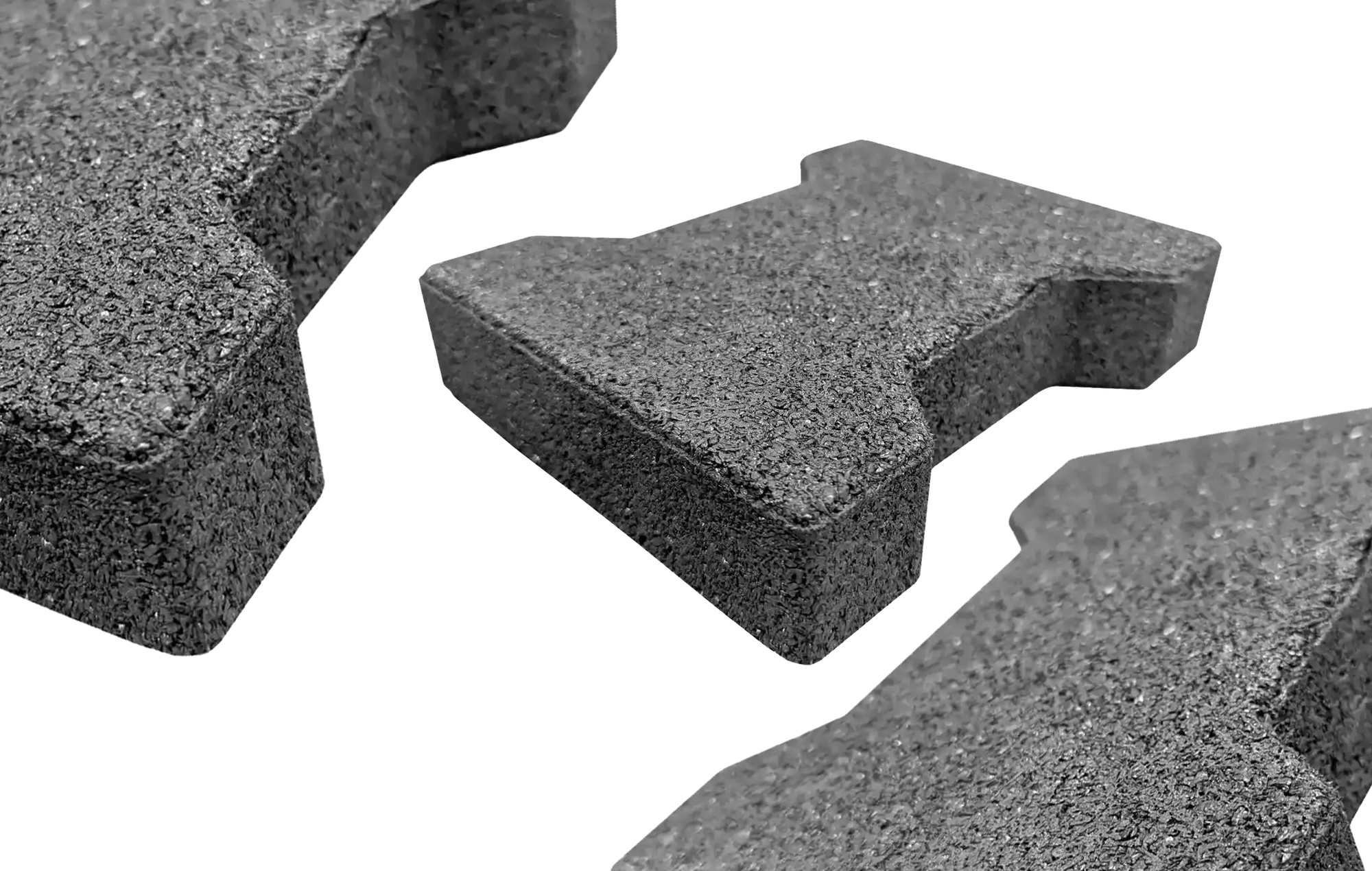 Three gray rubber pavers with one centered and further away and two on the edges not fully in the frame and closer to the camera