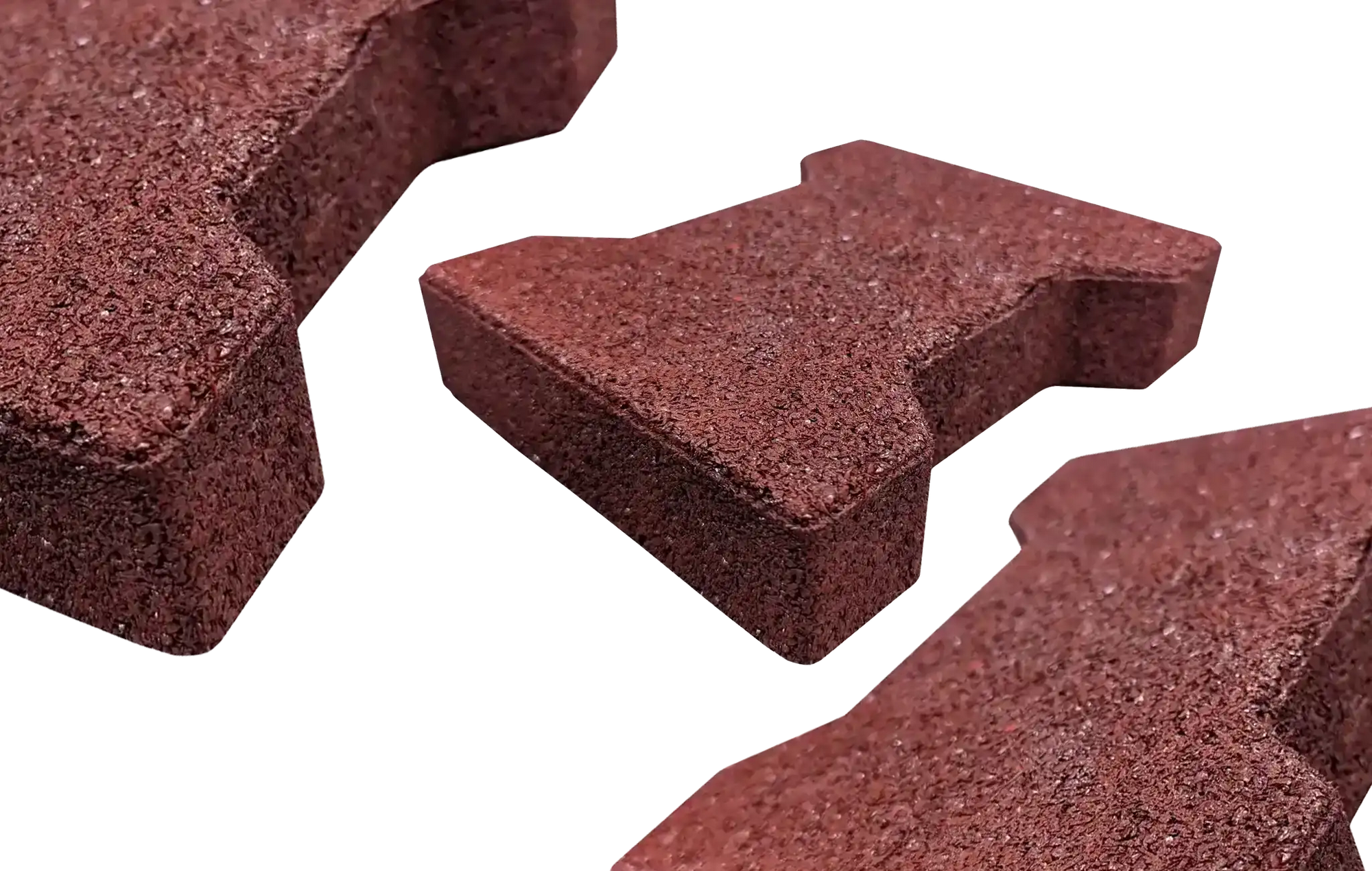 Three red rubber pavers with one centered and further away and two on the edges not fully in the frame and closer to the camera