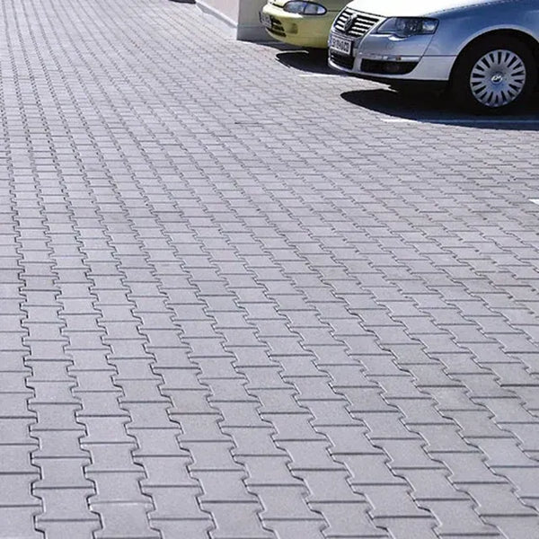 An outdoor parking lot with two cars parked on the rubber paver surface making up the parking lot