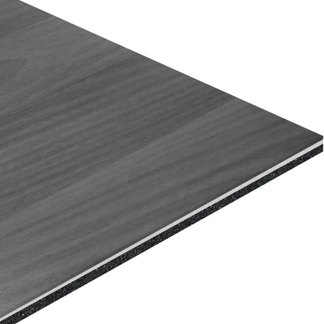 A close-up shows the corner of the ECORE Bounce 2 Motivate Laminate Roll - 7mm Class 1 Flooring by ECORE Athletic, highlighting its thin, rectangular shape, gray wood grain pattern, and visible layered edges.