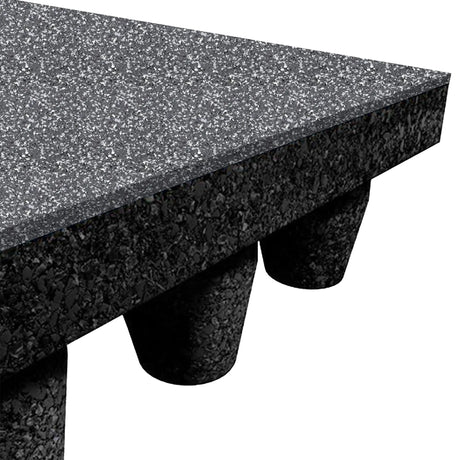 Close-up of an ECORE Athletic PlayGuard Rubber Tile - 2.5" Playground Flooring in black and gray speckle, showing its textured underside and support by black, rounded conical legs.