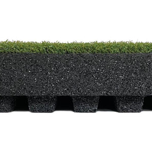 A close-up side view of the ECORE RageTurf dBTile - 2.5" Athletic Turf Tile by ECORE Athletic shows artificial grass on top, a thick textured black rubber layer in the middle, and evenly spaced black rubber feet at the bottom.