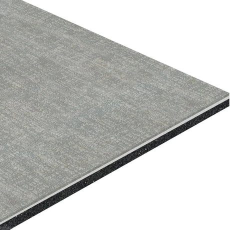 A close-up of the ECORE Restorative Motivate Laminate Roll - 7mm Class 1 Flooring by ECORE Athletic, showcasing its rectangular gray design, textured surface, layered construction with a black core, and visible thickness from an angle.