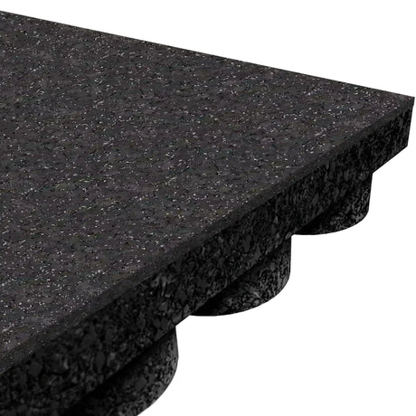 Close-up of the ECORE Performance UltraTile - 1" Rubber Tile by ECORE Athletic, showing its thick, rectangular black form with a speckled surface and rounded protrusions on the underside—ideal for athletic flooring.