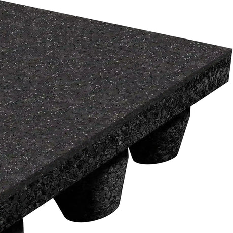 Close-up of ECORE Athletic's Performance dBTile Rubber Tile—2.5" thick acoustic flooring—with a textured black surface and rounded, raised supports underneath, shown angled against a white background.