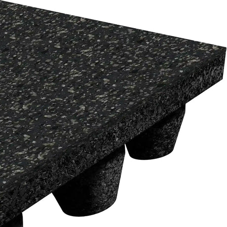 Close-up of the ECORE Athletic Performance dBTile Rubber Tile - 2.5" Acoustic Flooring showing its thick, speckled black textured surface and cylindrical supports underneath, angled to reveal both the top and underside.